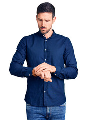 Wall Mural - Young handsome man wearing casual shirt checking the time on wrist watch, relaxed and confident