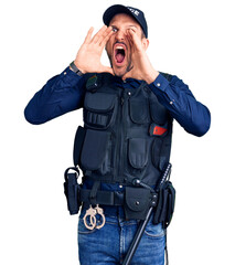 Canvas Print - Young handsome man wearing police uniform shouting angry out loud with hands over mouth