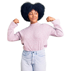 Sticker - Young african american girl wearing casual clothes showing arms muscles smiling proud. fitness concept.