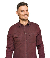 Sticker - Young hispanic man wearing casual clothes looking away to side with smile on face, natural expression. laughing confident.