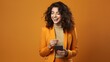 © Neuropixel - Happy young woman in yellow suit using smartphone isolated on orange, technology concept