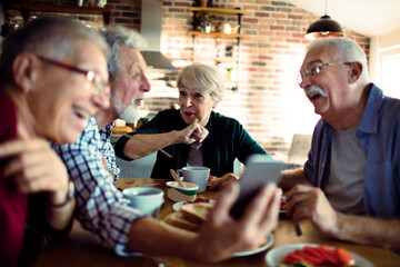 Wall Mural - Group of senior friends enjoying conversation and breakfast together