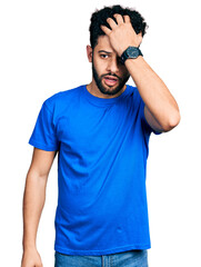 Canvas Print - Young arab man with beard wearing casual blue t shirt surprised with hand on head for mistake, remember error. forgot, bad memory concept.