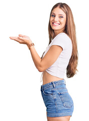 Wall Mural - Young beautiful blonde woman wearing casual white tshirt pointing aside with hands open palms showing copy space, presenting advertisement smiling excited happy