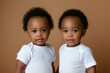 © Darya Lavinskaya - Cute African American identical twin toddlers against a pastel brown background
