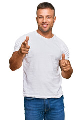 Handsome muscle man wearing casual white tshirt pointing fingers to camera with happy and funny face. good energy and vibes.