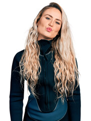 Canvas Print - Young blonde woman wearing diver neoprene uniform looking at the camera blowing a kiss on air being lovely and sexy. love expression.