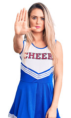 Canvas Print - Young beautiful blonde woman wearing cheerleader uniform doing stop sing with palm of the hand. warning expression with negative and serious gesture on the face.