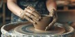 Dirty hands of young woman working on a pottery wheel sculpting mug with ceramic clay