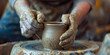 Dirty hands of young woman working on a pottery wheel sculpting mug with ceramic clay