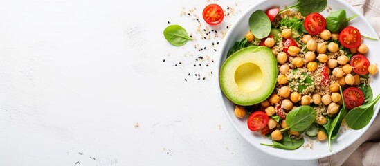 Wall Mural - Top view vegetable salad with quinoa, avocado, tomato, spinach, and chickpeas - on white table.