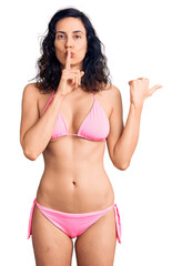 Sticker - Young beautiful hispanic woman wearing bikini asking to be quiet with finger on lips pointing with hand to the side. silence and secret concept.