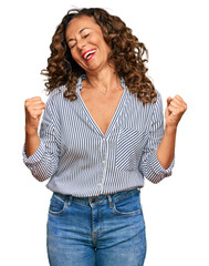 Canvas Print - Middle age hispanic woman wearing casual clothes very happy and excited doing winner gesture with arms raised, smiling and screaming for success. celebration concept.