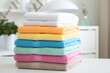 Colorful folded bath towels on white table in bedroom
