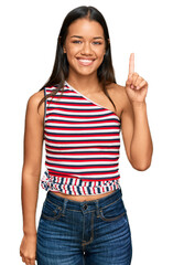 Canvas Print - Beautiful hispanic woman wearing casual clothes showing and pointing up with finger number one while smiling confident and happy.