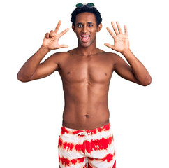 Wall Mural - African handsome man wearing swimsuit and sunglasses showing and pointing up with fingers number eight while smiling confident and happy.