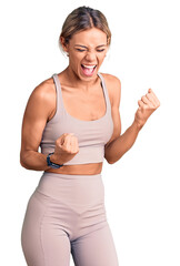 Wall Mural - Beautiful caucasian woman wearing sportswear celebrating surprised and amazed for success with arms raised and eyes closed. winner concept.