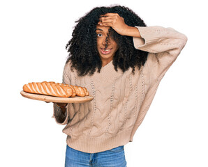 Poster - Young african american girl holding tray with bread stressed and frustrated with hand on head, surprised and angry face