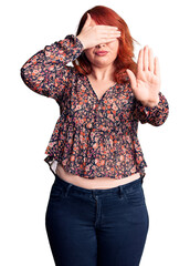 Wall Mural - Young beautiful redhead woman wearing casual t-shirt covering eyes with hands and doing stop gesture with sad and fear expression. embarrassed and negative concept.