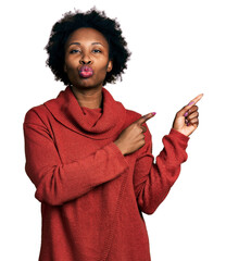 Wall Mural - African american woman with afro hair pointing with fingers to the side looking at the camera blowing a kiss being lovely and sexy. love expression.