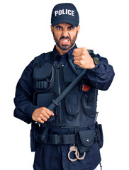 Wall Mural - Young hispanic man wearing police uniform holding baton annoyed and frustrated shouting with anger, yelling crazy with anger and hand raised