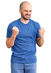 Canvas Print - Young handsome man wearing casual t shirt very happy and excited doing winner gesture with arms raised, smiling and screaming for success. celebration concept.