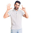 © Krakenimages.com - Young handsome man with beard wearing casual polo showing and pointing up with fingers number seven while smiling confident and happy.