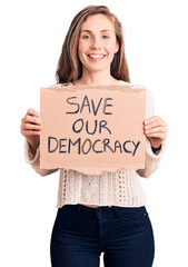 Sticker - Young beautiful blonde woman holding save our democracy banner looking positive and happy standing and smiling with a confident smile showing teeth