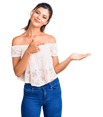 Sticker - Young beautiful woman wearing casual clothes amazed and smiling to the camera while presenting with hand and pointing with finger.