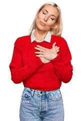 Wall Mural - Young blonde woman wearing casual clothes smiling with hands on chest with closed eyes and grateful gesture on face. health concept.