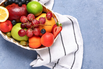 Wall Mural - Wicker bowl with different fresh fruits on blue background