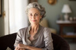 © aicandy - Elegant older woman with hazel eyes and beautiful gray hair sitting peacefully in her vintage-styled living room, bathed in the warm evening sunlight