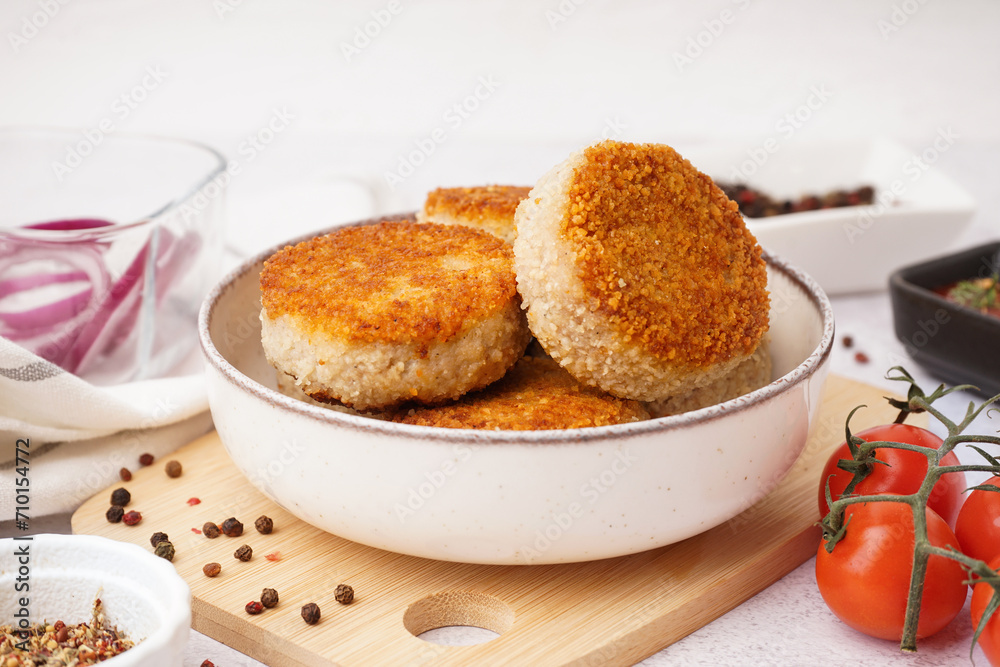 Bowl of tasty meat cutlets on white background