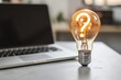 Light bulb with question mark sign and laptop, office in the background, curiosity, ideas and technology concept.