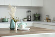 Wooden table with tea set, dried flowers and eucalyptus branches in modern kitchen