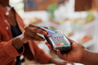 © DC Studio - Black person using credit card to make contactless payment for fresh organic produce at a local market. Closeup of african american customer doing cashless transaction at grocery store