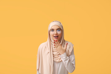 Sticker - Shocked young Muslim woman in hijab and eyeglasses on yellow background