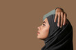 Young African-American Muslim woman with beautiful makeup on brown background