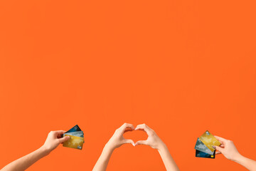 Poster - Women with credit cards making heart gesture on orange background