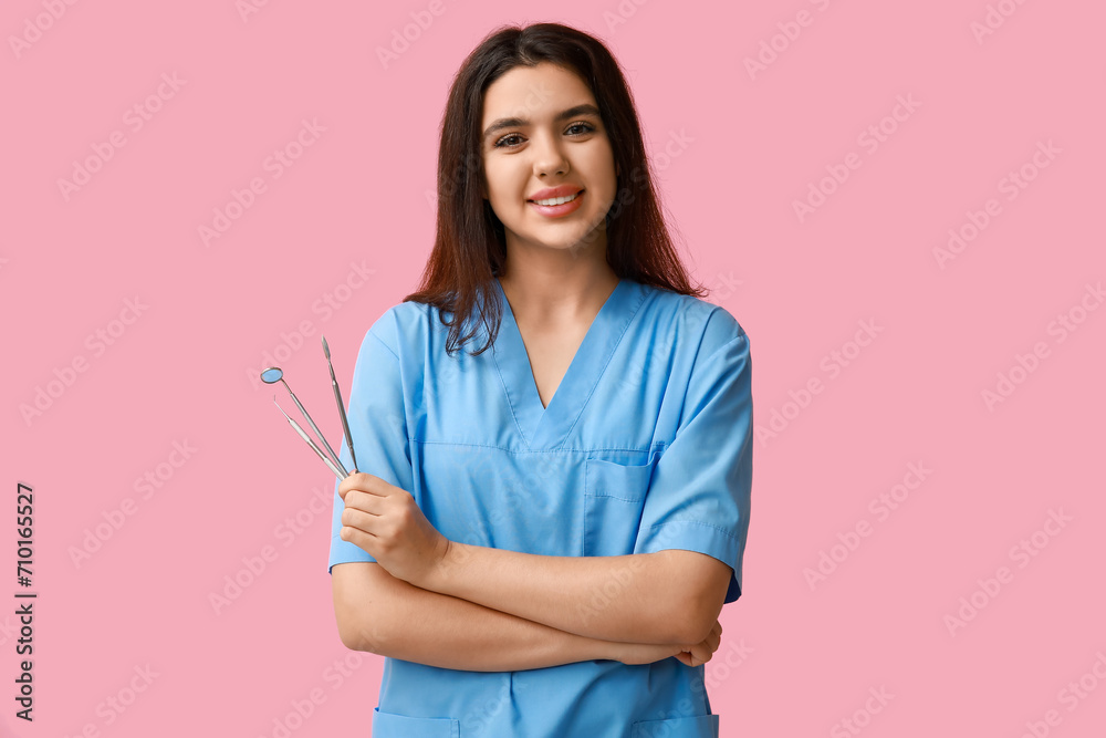 Female dentist with tools on pink background. World Dentist Day