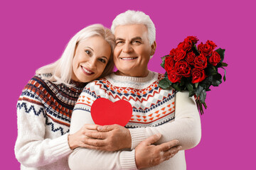 Wall Mural - Happy mature couple with paper heart and bouquet of roses on purple background