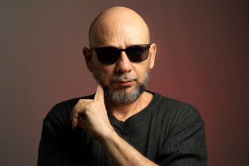 Wall Mural - White, bald man, wearing sunglasses, confident and serious looking towards the camera.