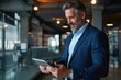 © Lumina Frame - Happy mid aged business man ceo wearing blue suit standing in office using digital tablet. Mature businessman professional executive manager holding tab working on financial data on dev, Generative AI