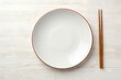 Ceramic plate and chopsticks on white table