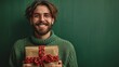 A young happy, cheerfully smiling man of 20 years old in a green sweater holds in his hands a gift