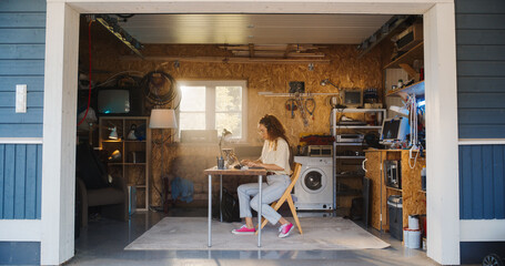 Fototapete - Hispanic Female Software Developer Programming On Laptop Computer In Garage At Home. Focused Young Woman Working On Innovative Online Service Startup Company, Coding. Digital Entrepreneur Concept.