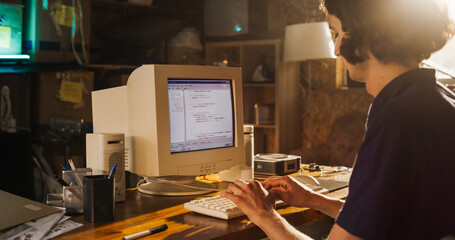 Fototapete - Side View Of Caucasian Male Software Engineer Programming on Old Desktop Computer In Retro Garage. Focused Man Starting Tech Startup Company In Nineties. Coding Innovative Online Service At Home.