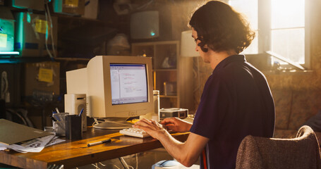 Caucasian Male Software Engineer Programming on Old Desktop Computer In Retro Garage. Focused Man Starting Fintech Startup Company In Nineties. Coding Innovative Online Service At Home.