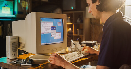 Leinwandbilder - Caucasian Male College Student Using Old Desktop Computer In Nineties Retro Garage. Young Programmer Connecting World Wide Web Via Early Internet Software, Exploring Global Network.