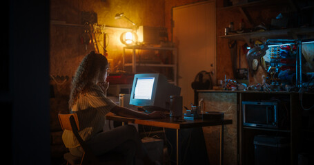 Leinwandbilder - Hispanic Female Web Designer Using Old Desktop Computer In Retro Garage Late At Night. Focused Internet Enthusiast Writing Code At Home. Programming Successful Social Network Website In Nineties.
